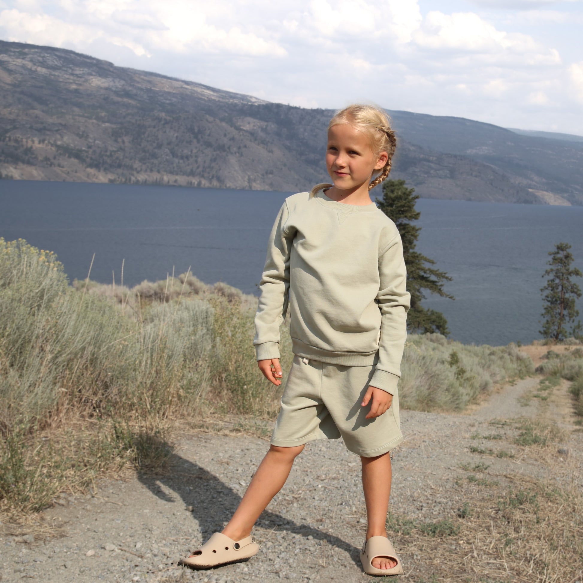 Child wearing sage green french terry shorts – side view with elastic waist