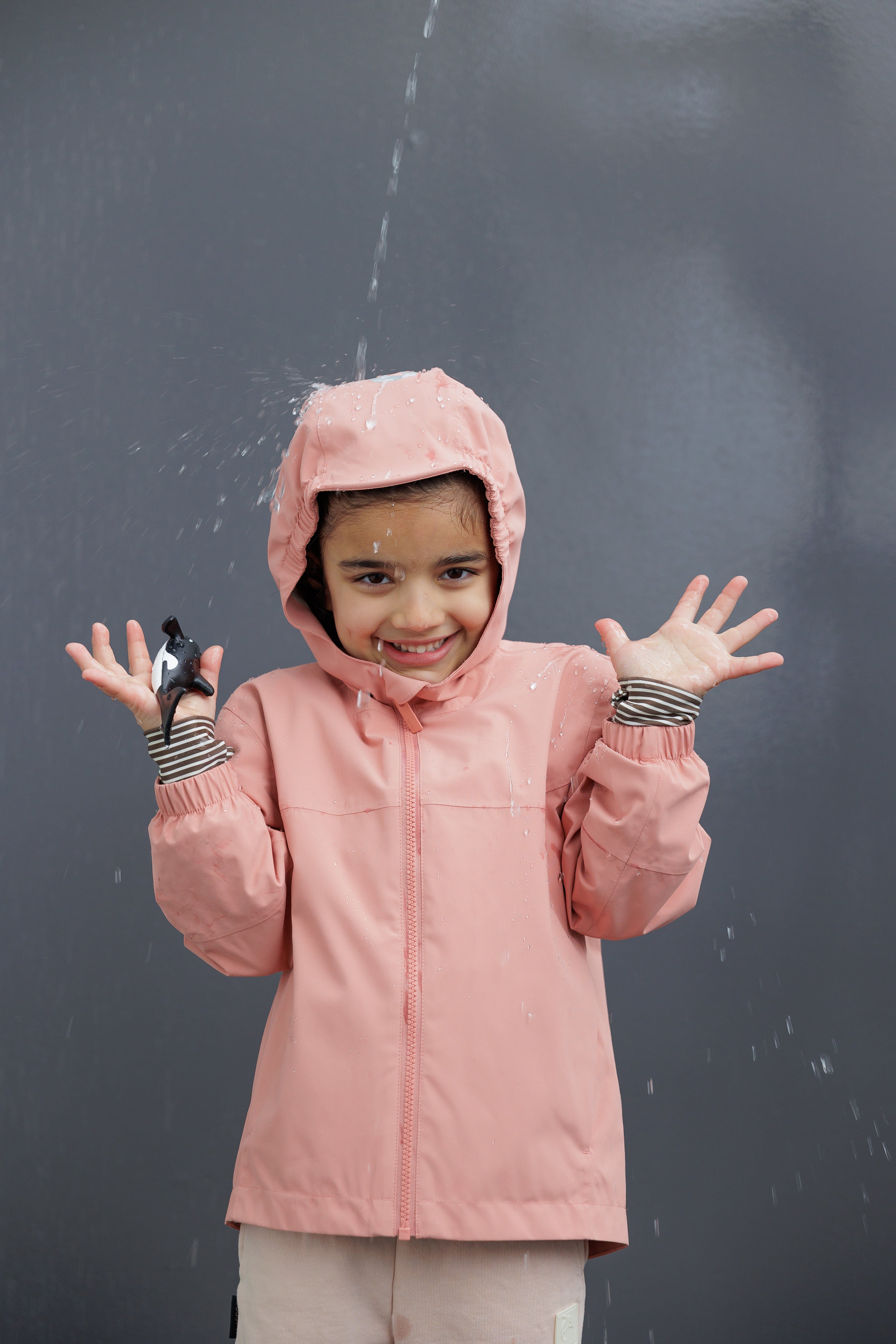 Kids wearing KidORCA waterproof rain jackets and pants splashing in puddles