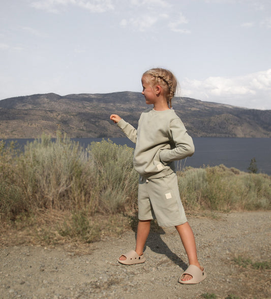 Child wearing dusty olive french terry shorts – side view with elastic waistband